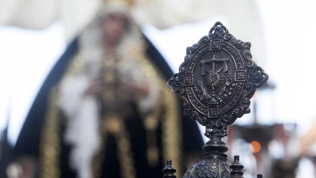 Escudo de la hermandad de la Soledad, con la Virgen al fondo