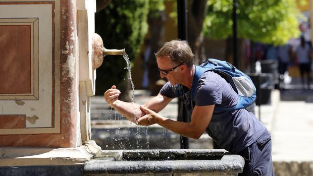 Un hombre se refresca en una fuente en Córdoba