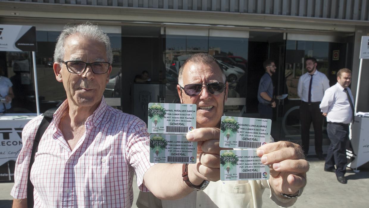 Dos aficionados del Córdoba CF posan con los abonos de este curso