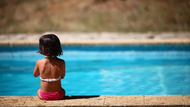 Una niña descansa al borde de una piscina sin atención