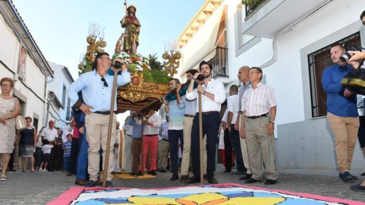 Procesión de San Roque en Dos Torres, frente a una alfombra de sal coloreada en la calle