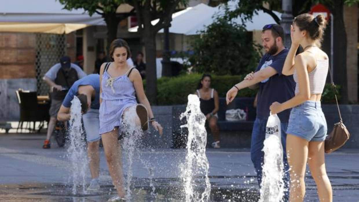 Varias personas se refrescan en las fuentes de la plaza de las Tendillas de Córdoba
