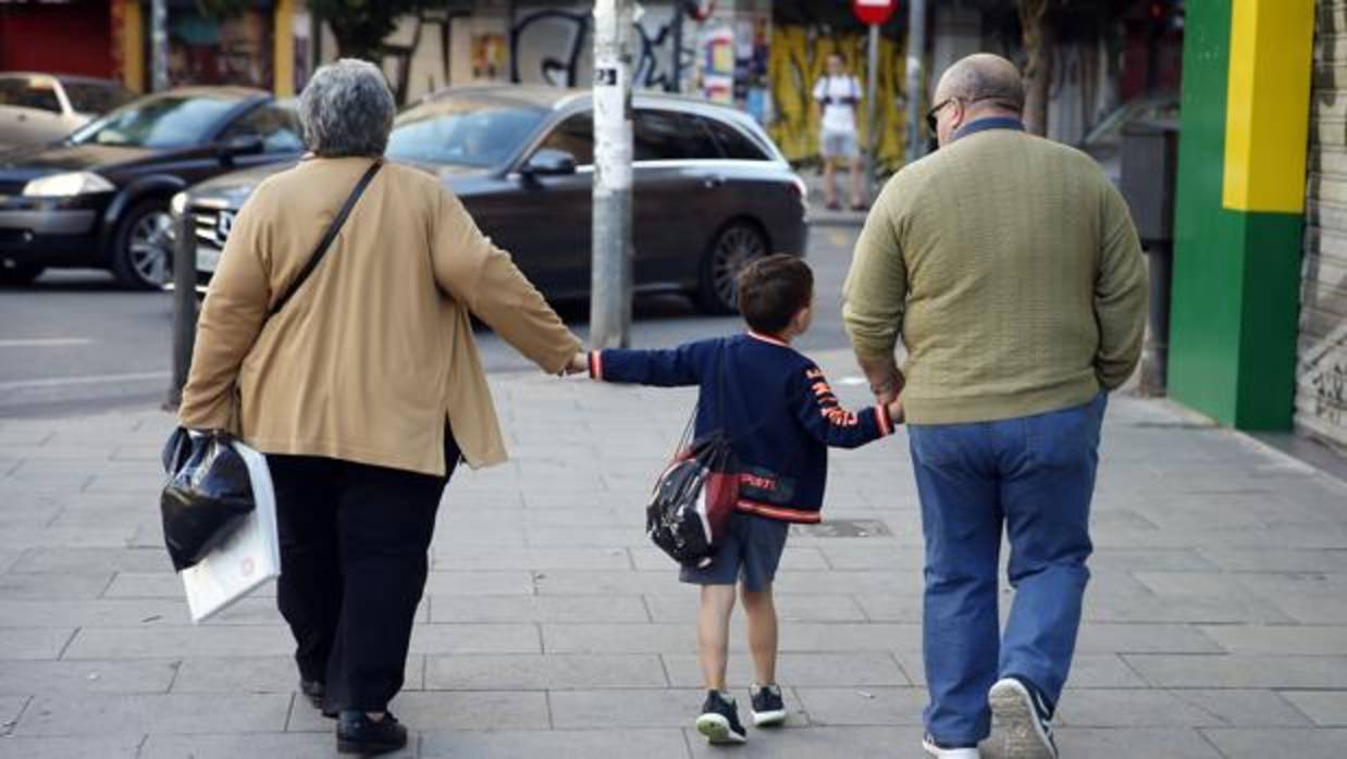 Dos abuelos, con su nieto camino del colegio