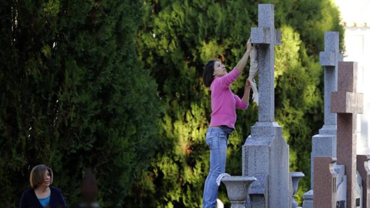 Una mujer limpia una tumba en el cementerio de la Salud