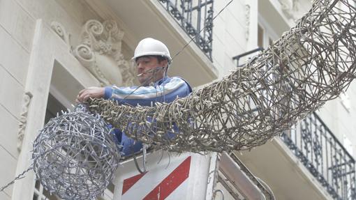 Un operario coloca el ornato eléctrico navideño en una calle