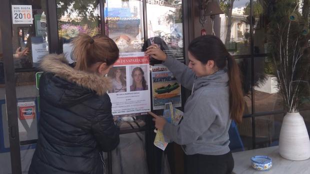 Dos colaboradores de la familia pegando carteles en Tavira (Portugal)