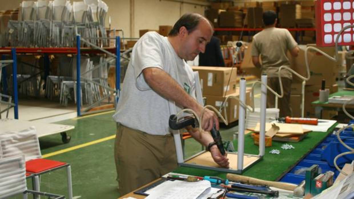 Un trabajador monta una silla en una fábrica de muebles