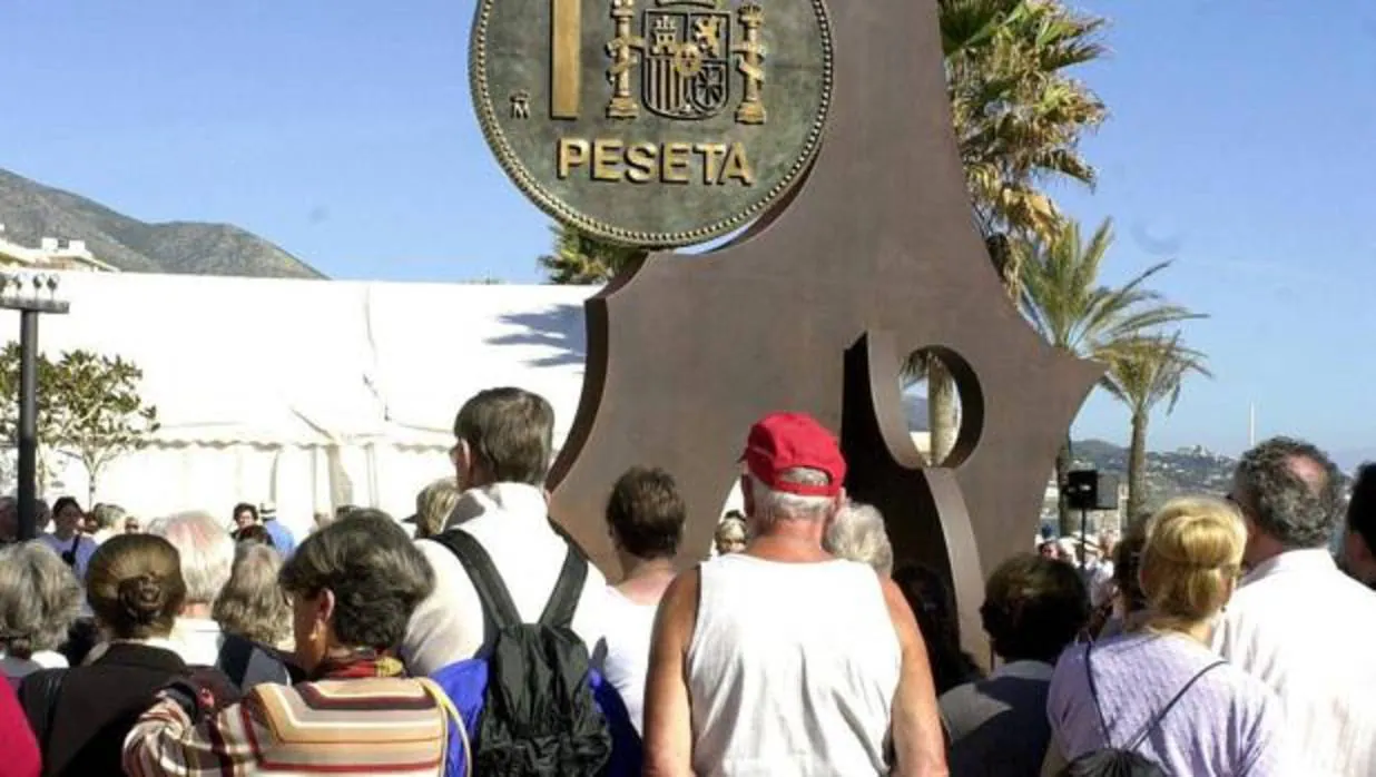 Turistas frente al monumento a la peseta en el paseo marítimo de Fuengirola