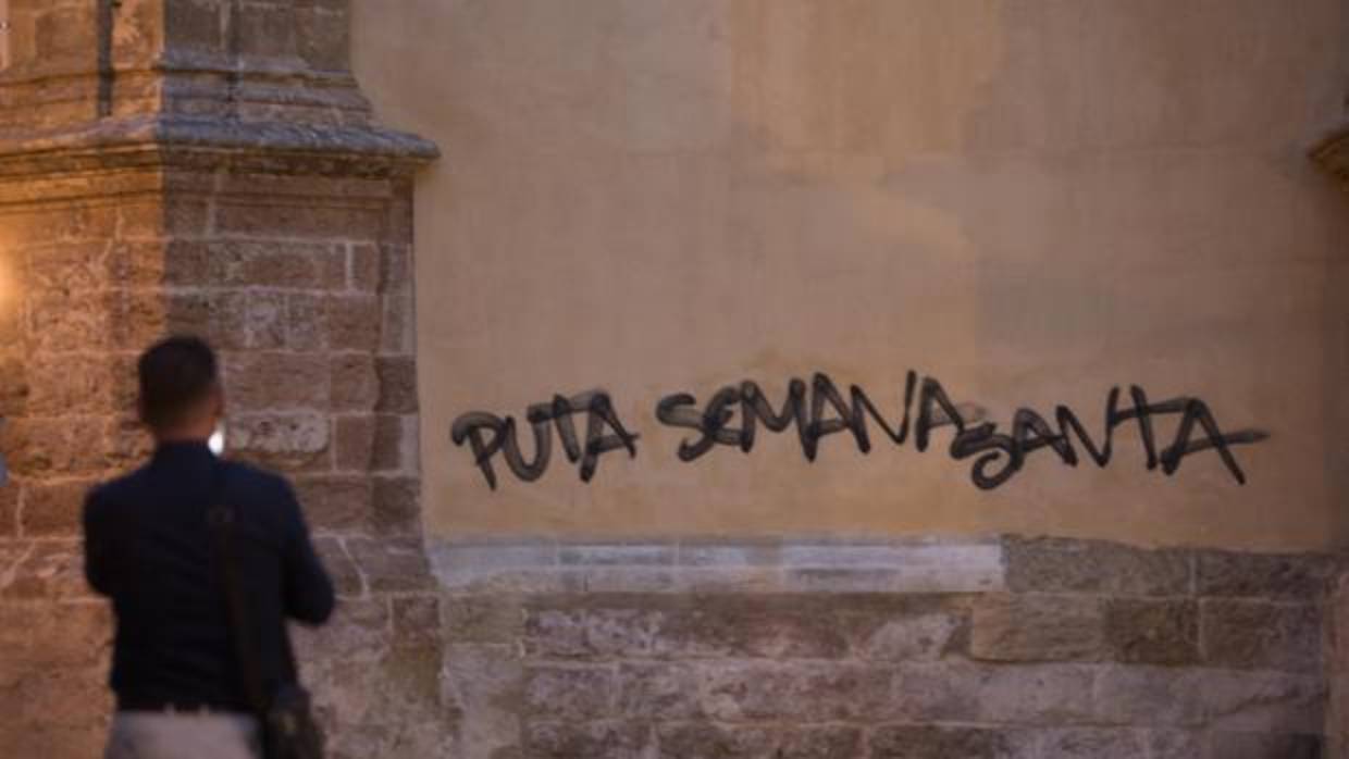 Un turista contempla la pintada en la fachada de la basílica de San Pedro