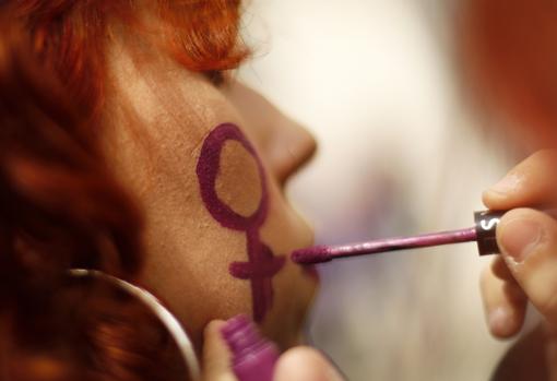 Una mujer se pinta un símbolo feminista durante una protesta