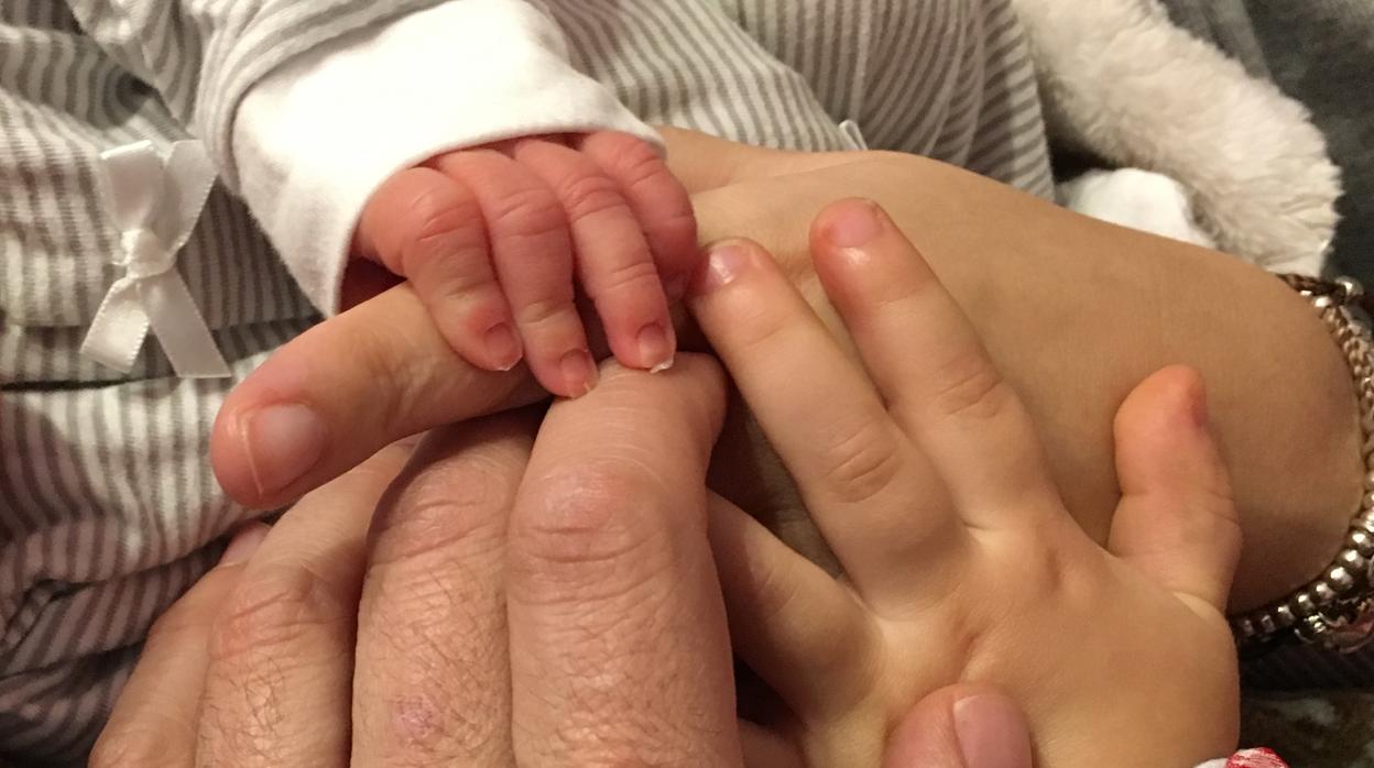 La mano del pequeño Miguel junto a la de sus padres y su hermano