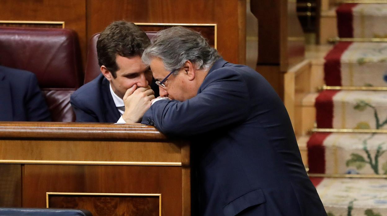 El nuevo presidente del PP, Pablo Casado, comparte confidencias con Juan Ignacio Zoido en su escaño del Congreso