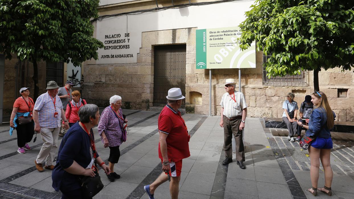 Un grupo de turistas pasan frende a la fachada del Palacio de Congresos