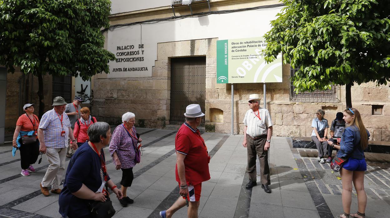 Un grupo de turistas pasan frende a la fachada del Palacio de Congresos