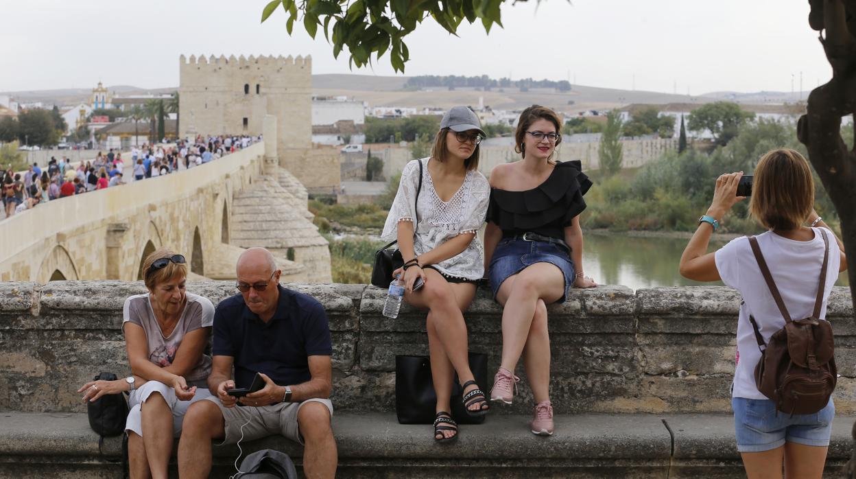 Dos turistas se fotografían con el Puente Romano y la Torre de la Calahorra, al fondo