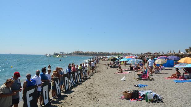 Centenares de personas forman una cadena humana contra un fondeadero de buques frente a Sotogrande