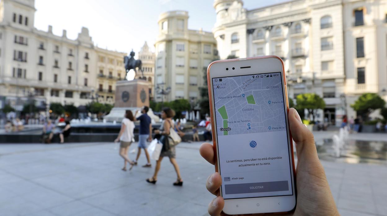 Una usuaria descarga la aplicación de Uber en la plaza de las Tendillas, aún no operativa