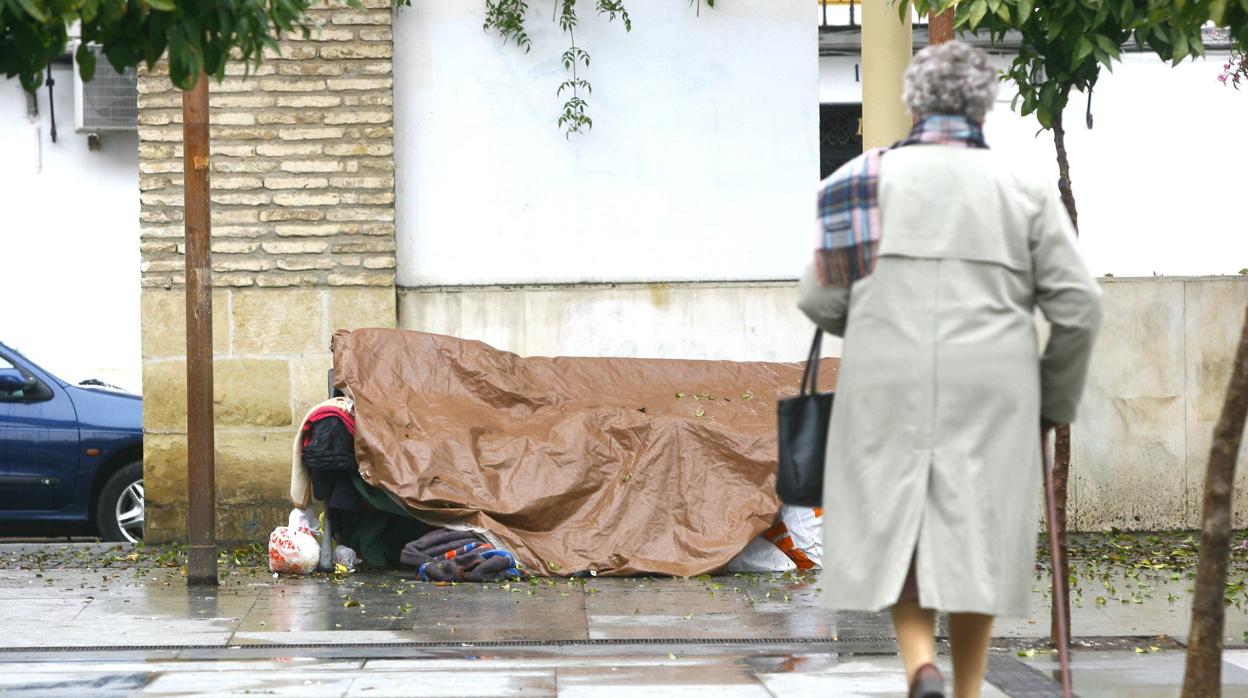 Una mujer camina delante del cobijo de una persona sin hogar