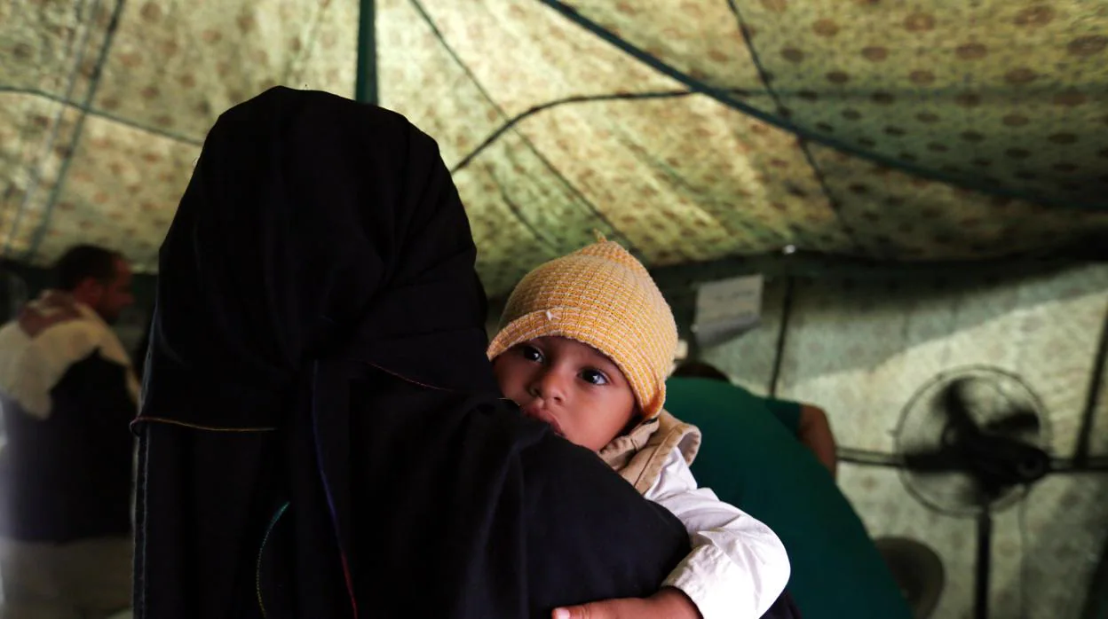Una madre sostiene a su hijo enfermo de cólera en un hospital de campaña en Yemen