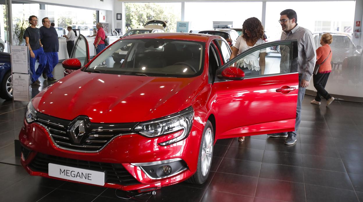 El empleado de un concesionario muestra un coche a un posible comprador