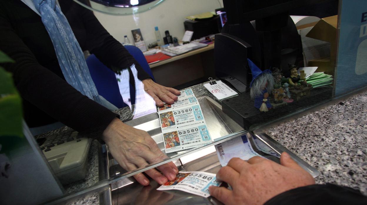 Un cliente recoge billetes de lotería en una administración