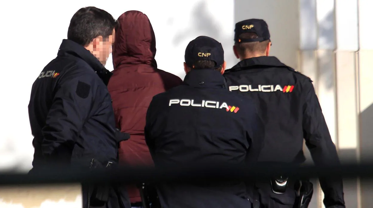 Tres policías llevan al joven acusado de violación ante el juez