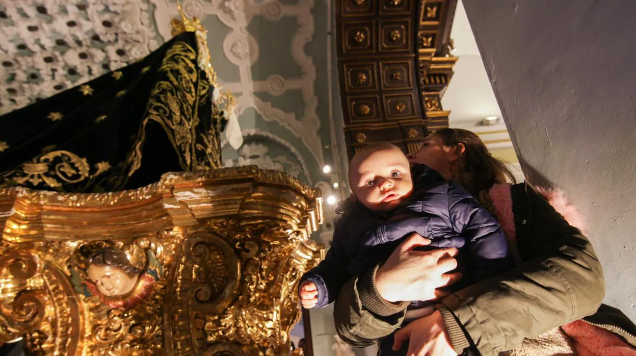 Los niños pasan bajo el manto de la Virgen de los Dolores de Córdoba, con motivo de la Candelaria