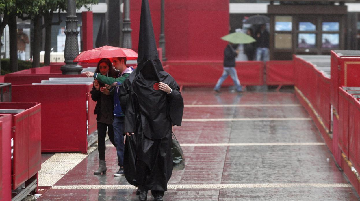 Nazareno de la hermanda del Santo Sepulcro pasa por la antigua Carrera Oficial de Córdoba, bajo la lluvia