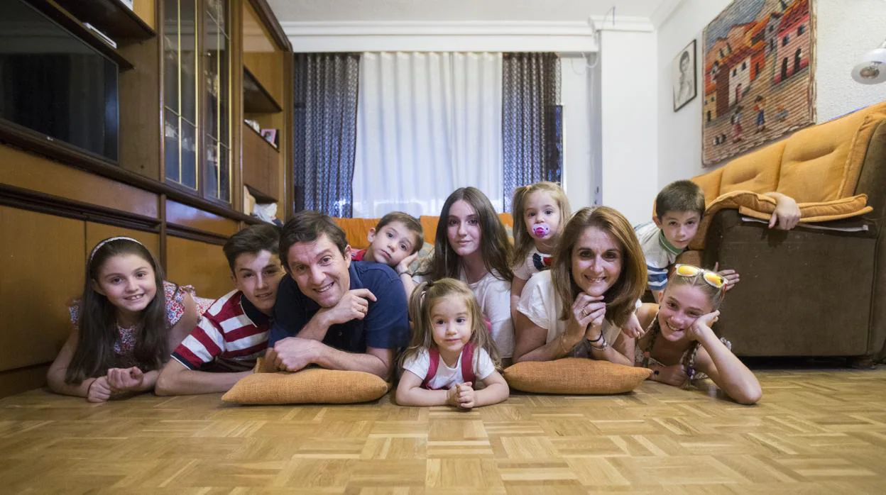 Un matrimonio y sus ocho hijos posan en el salón de su casa