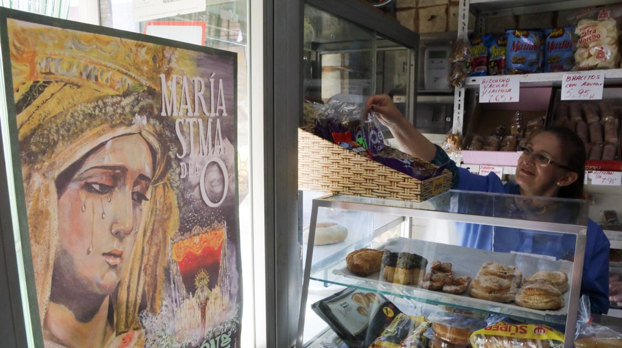 Araceli en su tienda de ultramarinos con un cartel anunciando la procesión de la Virgen de la O