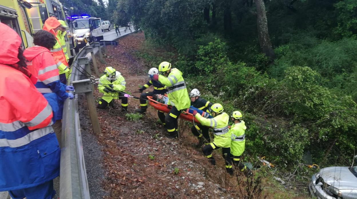 Los bomberos trasladan al herido a la ambulancia por el terraplén