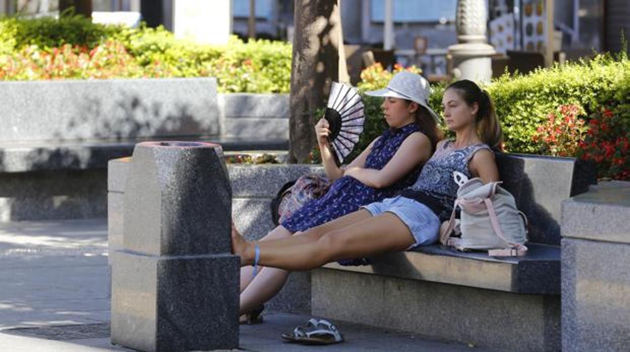 Dos turistas se refrescan en la plaza de Las Tendillas