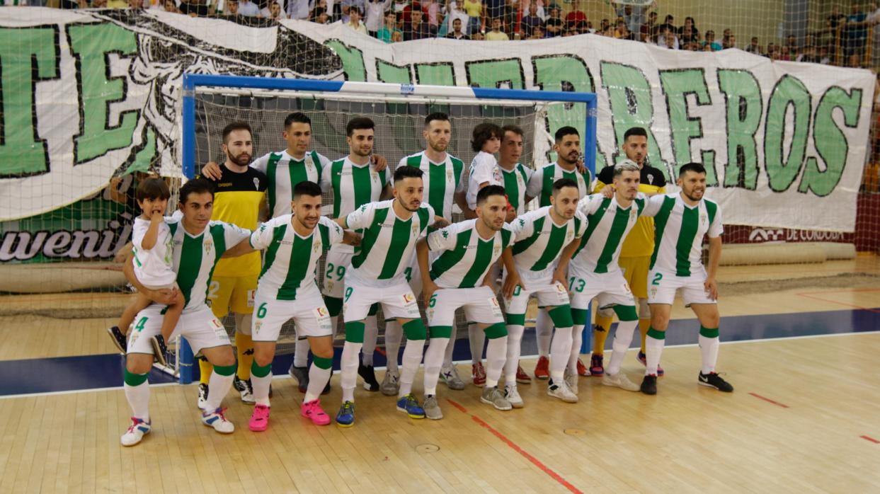 La plantilla del Córdoba Futsal, ante una pancarta de la afición