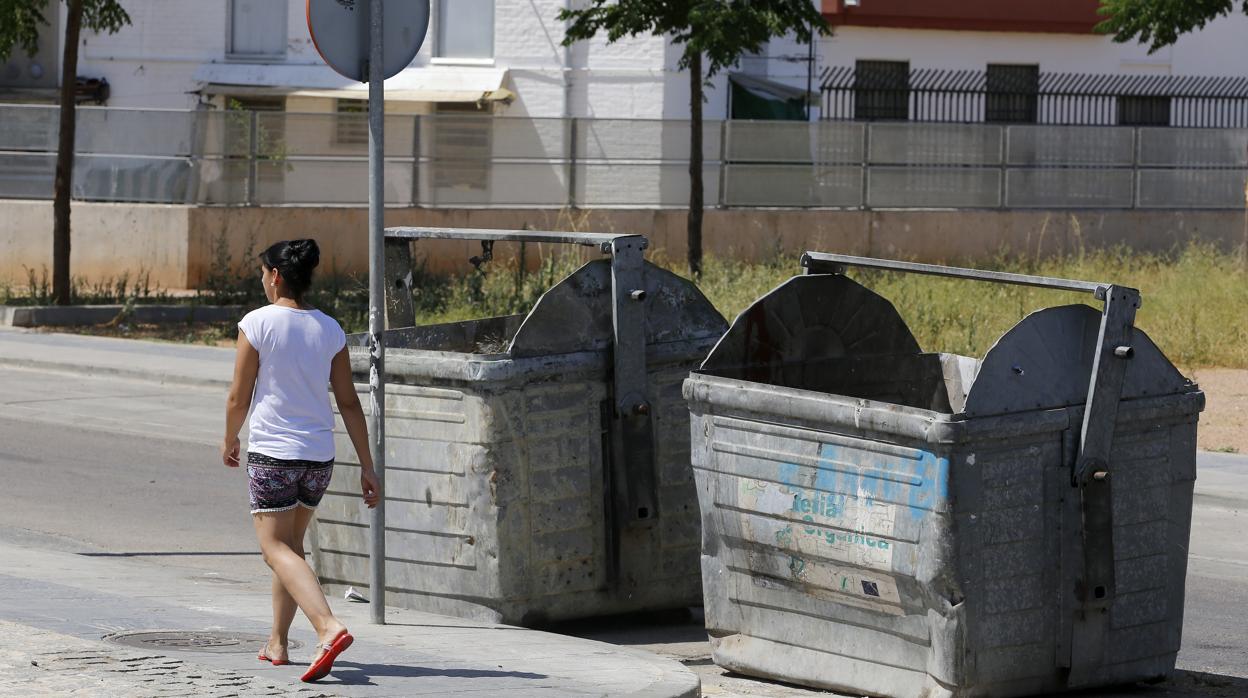 Una mujer pasa delante de dos contenedores quemados en la zona Sur