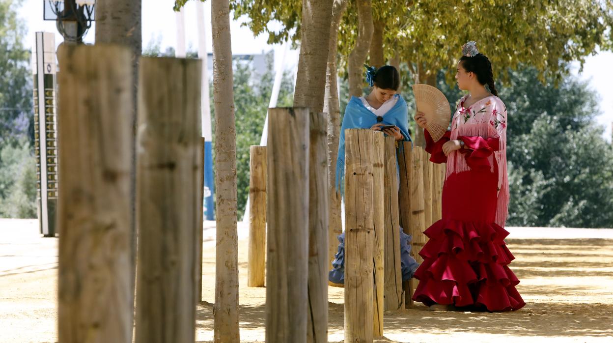 Dos chicas vestidas de gitana se abanican en el Arenal