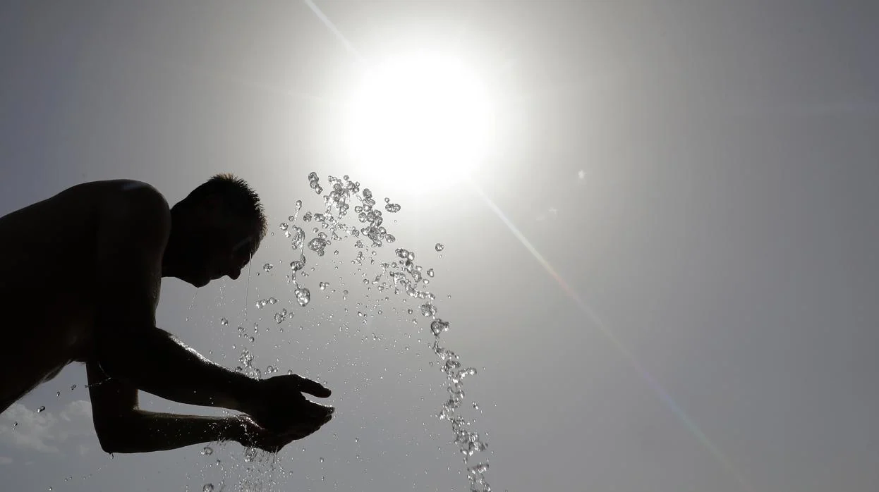 Un hombre se refresca en una fuente en plena ola de calor
