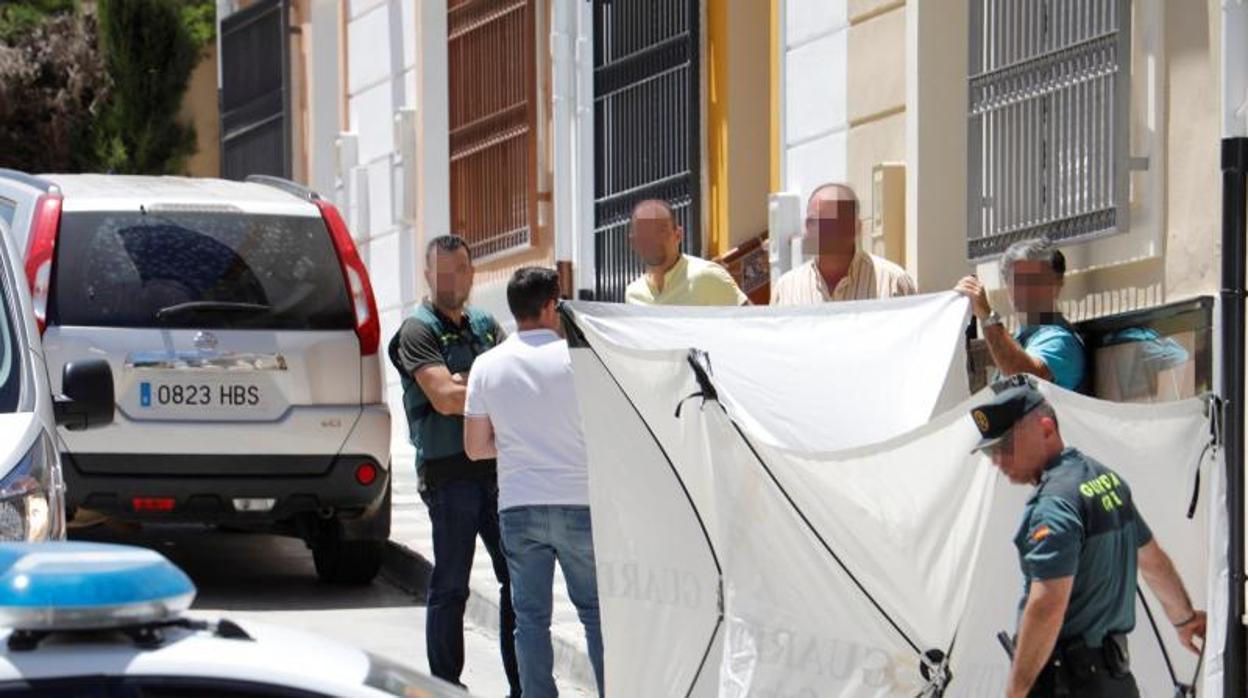 Agentes de la Guardia Civil tapan con una lona el portal de la casa donde se produjo el crimen en Rute