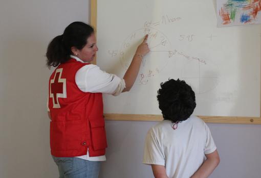 Una voluntaria de Cruz Roja Córdoba junto a uno de los menores