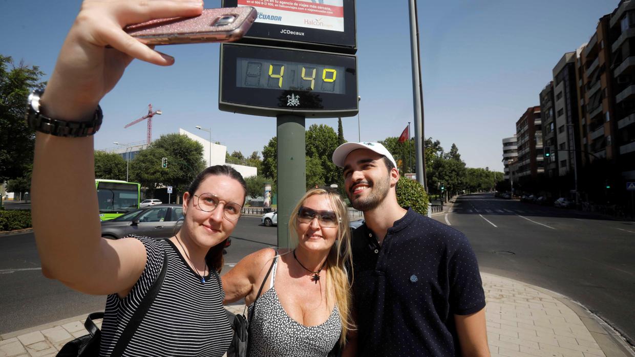 Unos turistas se fotografían con un termómetro del centro de Córdoba que indica 44 grados