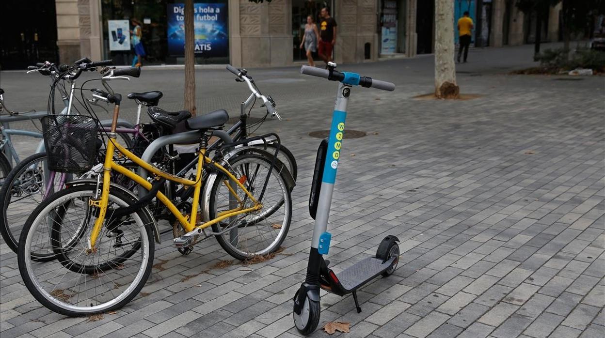 Patinete eléctrico, junto a bicicletas en la acera