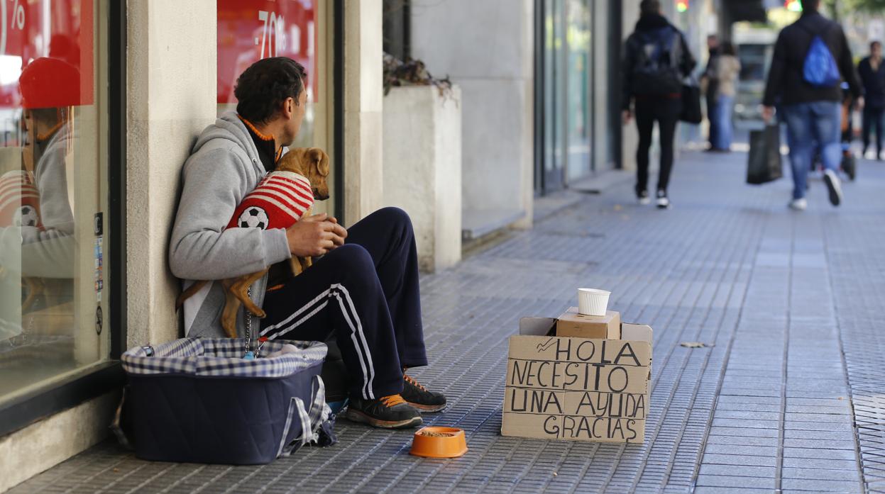 Una persona sin hogar pide limosna en una calle céntrica de Córdoba