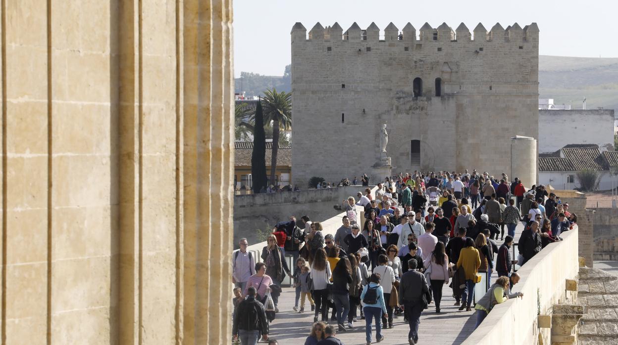 Varios turistas pasean sobre el puente romano de Córdoba