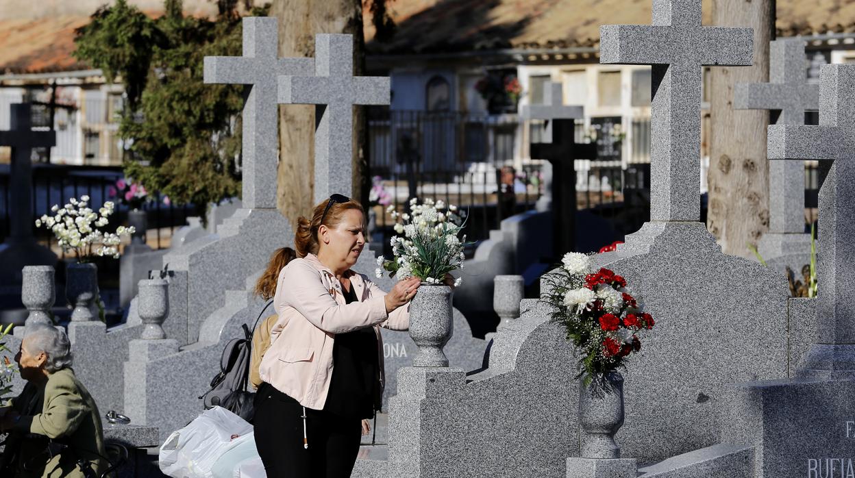 Una mujer coloca flores en una tumba el cementerio de San Rafael