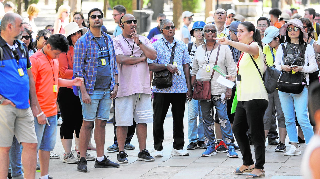 Un grupo de turistas atiende a su guí en el Patio de los Naranjos