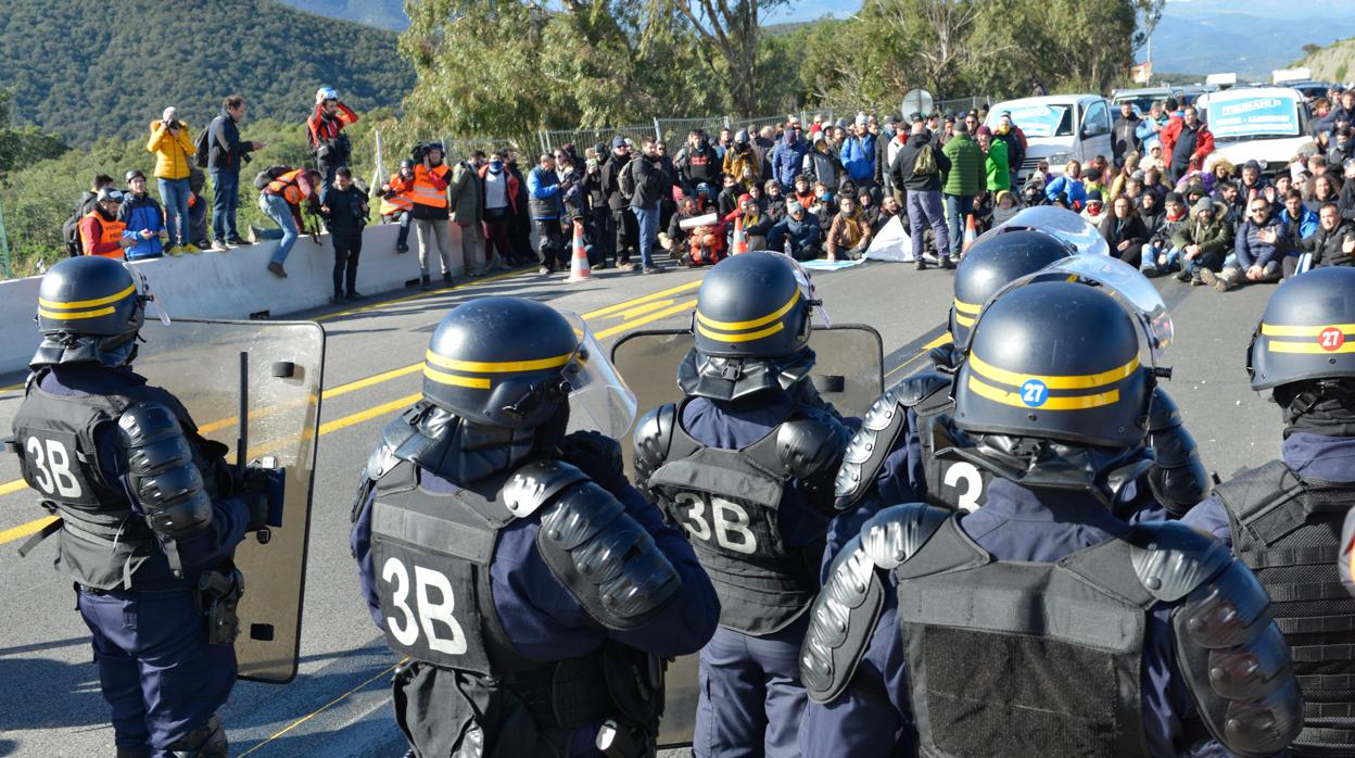 Agentes de la Policía frente a los manifestantes que cortan la carretera