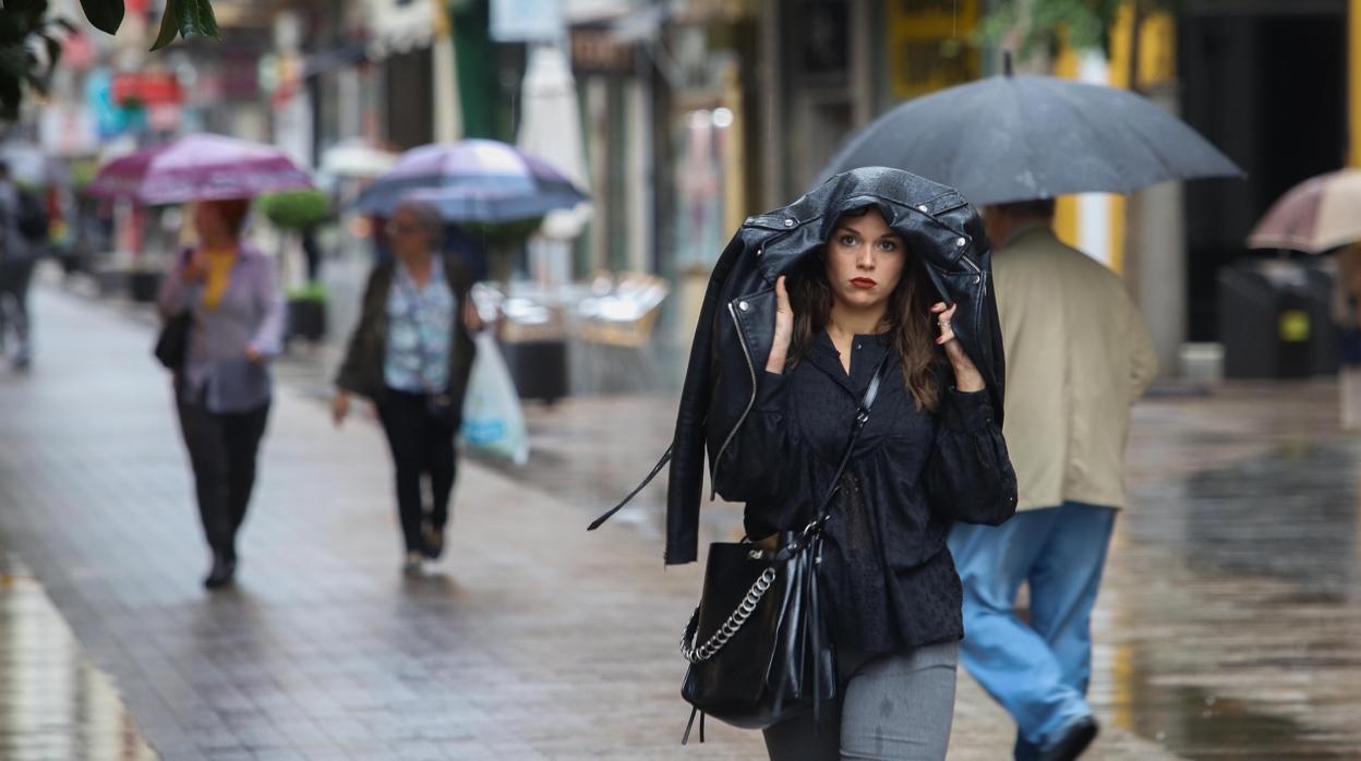 Una joven se refugia de la lluvia bajo su chaqueta