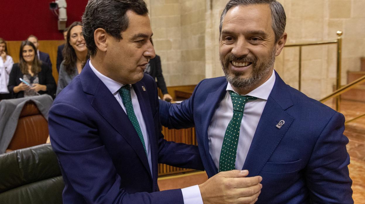 El presidente andaluz, Juanma Moreno (i), felicita al consejero de Hacienda, Juan Bravo (d)