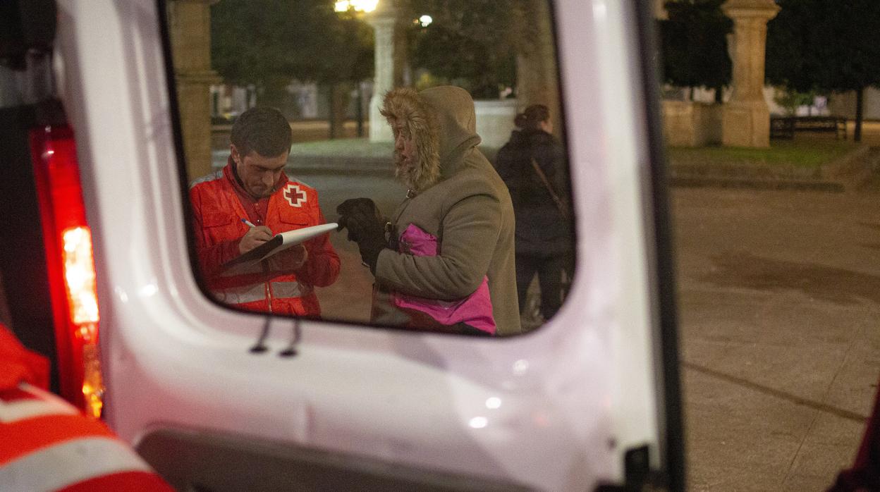 Un voluntario de Cruz Roja toma nota mientras habla con una mujer que vive en la calle