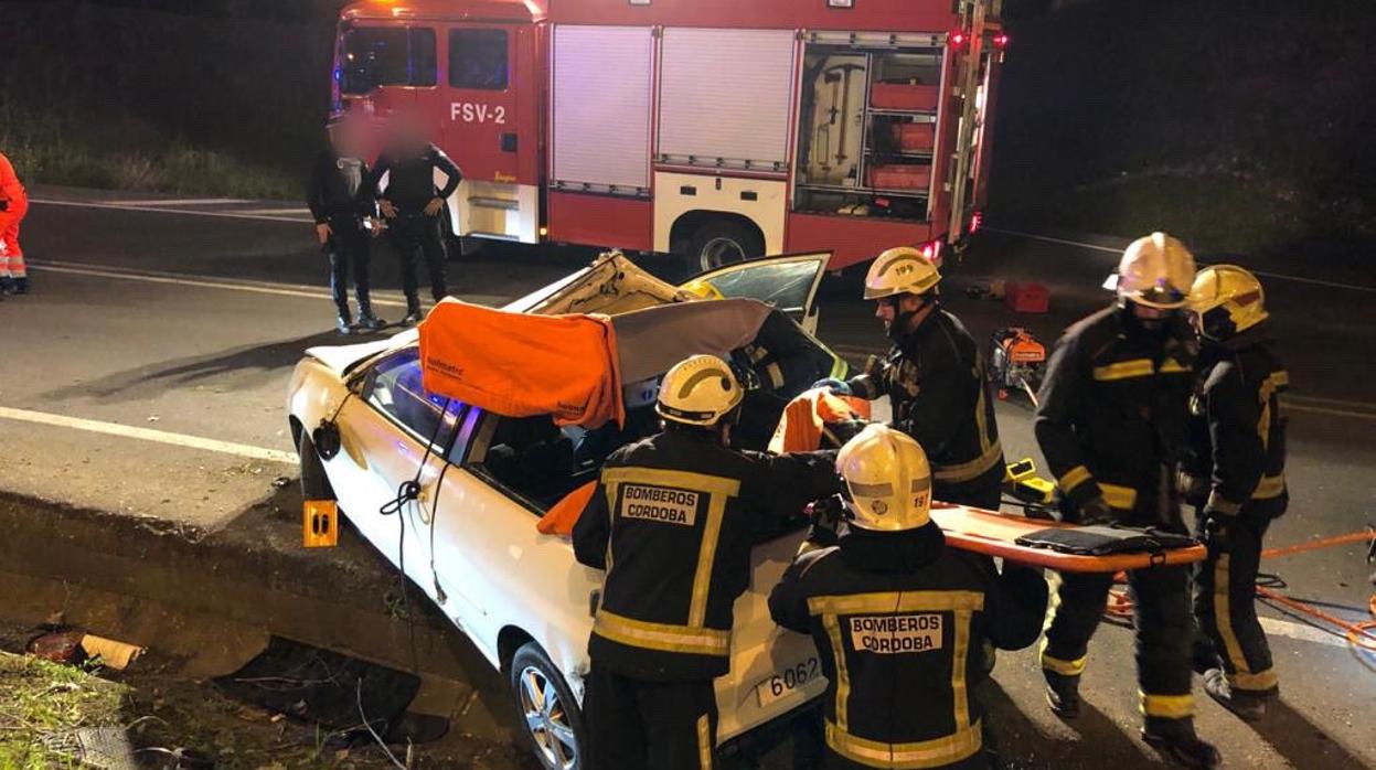 Los bomberos, durante el rescate del conductor herido