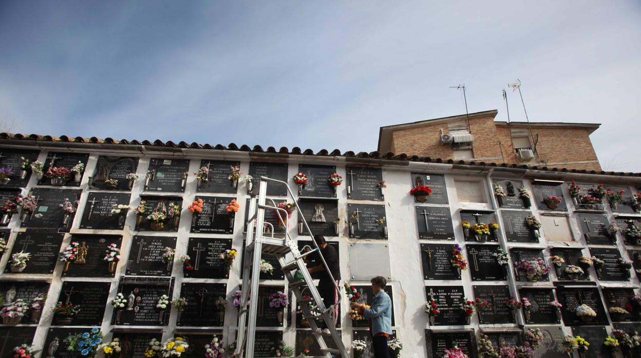 Una familia limpia una lápida en el cementerio de San Rafael